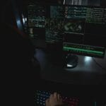 Ciemny pokój z monitorami wyświetlającymi kod związany z cyberbezpieczeństwem