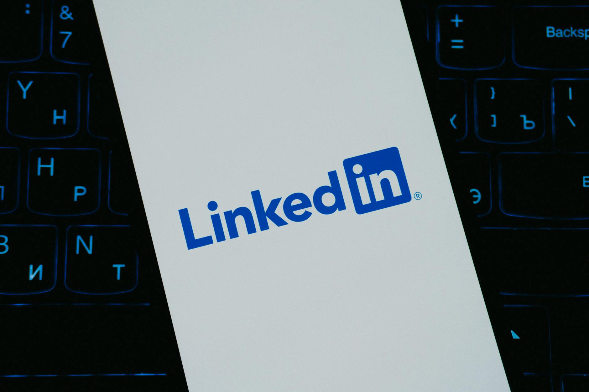Logo LinkedIn na ekranie smartfona na tle klawiatury
