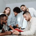 Jak dołączyć do projektu open source bez doświadczenia programistycznego Zespół programistów omawia pomysły przy stole w biurze