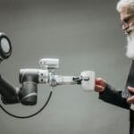 Czy sztuczna inteligencja stanie się obowiązkowym komponentem każdej firmowej infrastruktury IT Starszy mężczyzna odbiera kubek od ramienia robota w nowoczesnym biurze