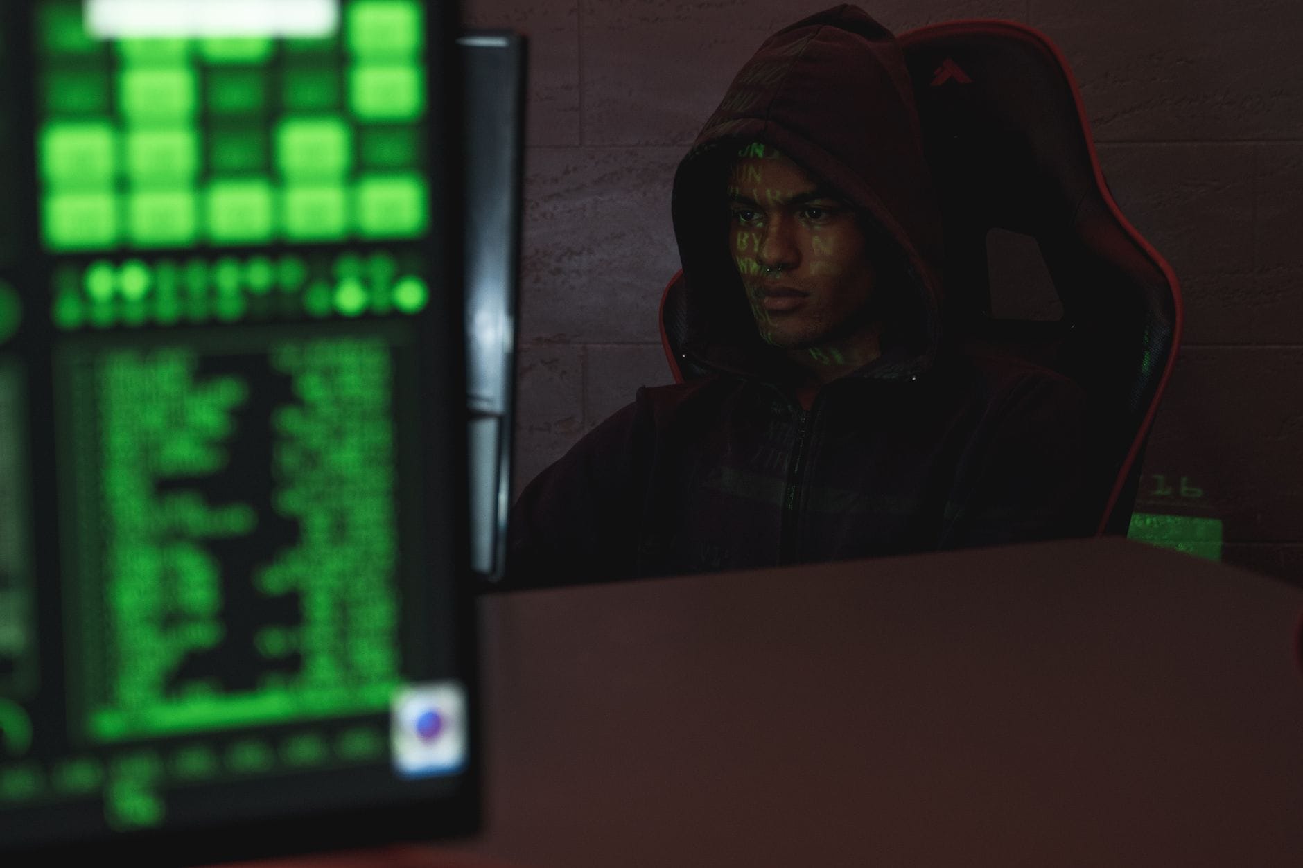 Zasłonięty kapturem specjalista cyberbezpieczeństwa pracuje przy komputerze
