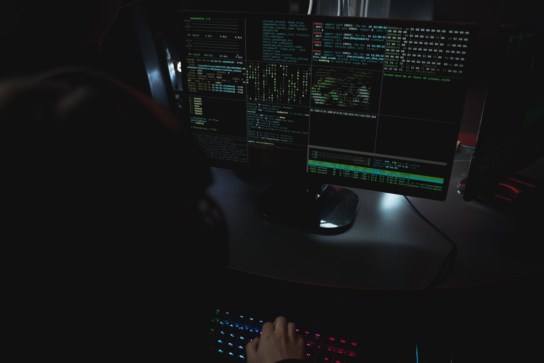 Ekrany komputerów z kodem w ciemnym pomieszczeniu symbolizujące cyberatak