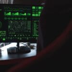 Monitor z zielonym kodem symbolizujący cyberatak na inteligentny dom